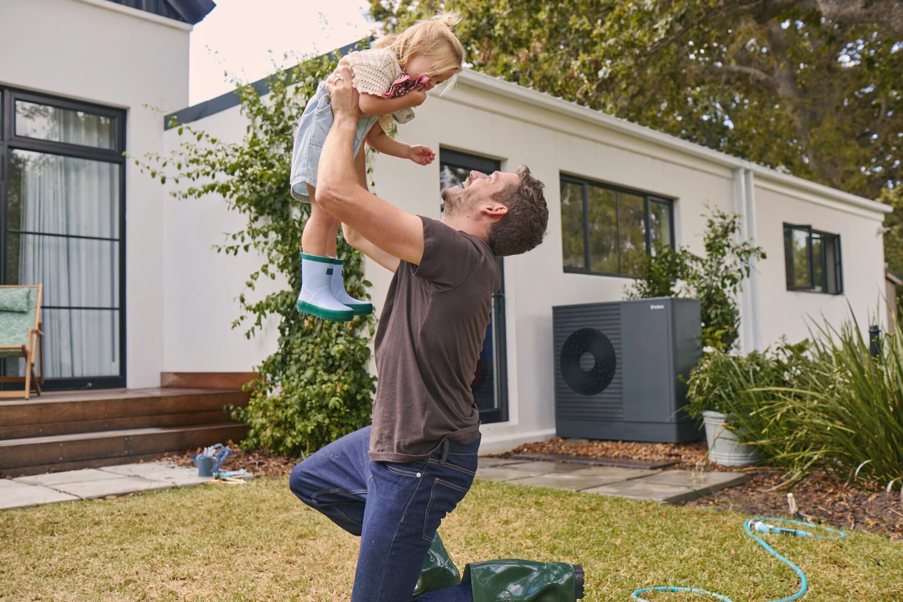 Vaillant ısı pompasının önünde bahçede çocuğuyla oynayan baba