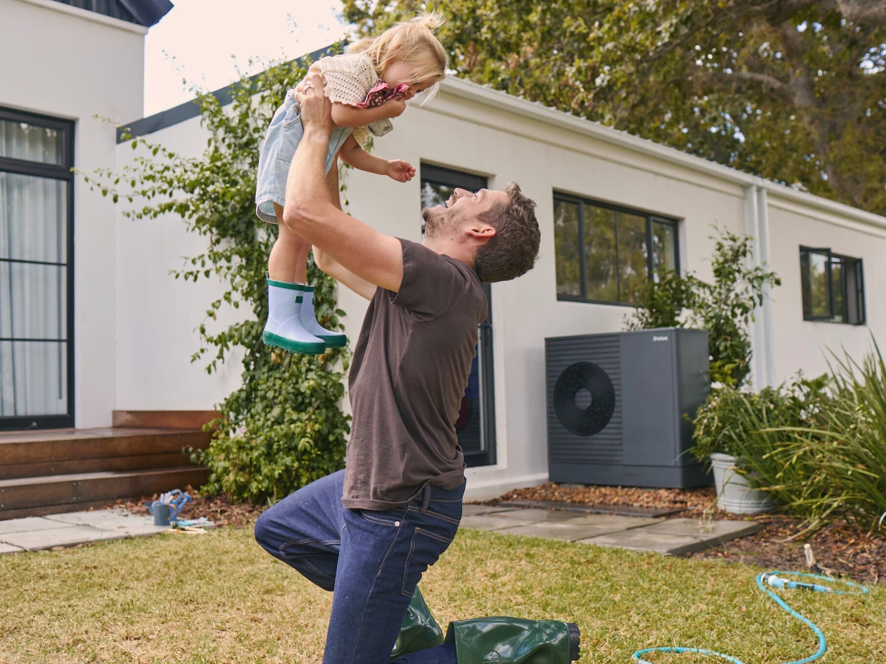 Vaillant ısı pompasının önünde bahçede çocuğuyla oynayan baba