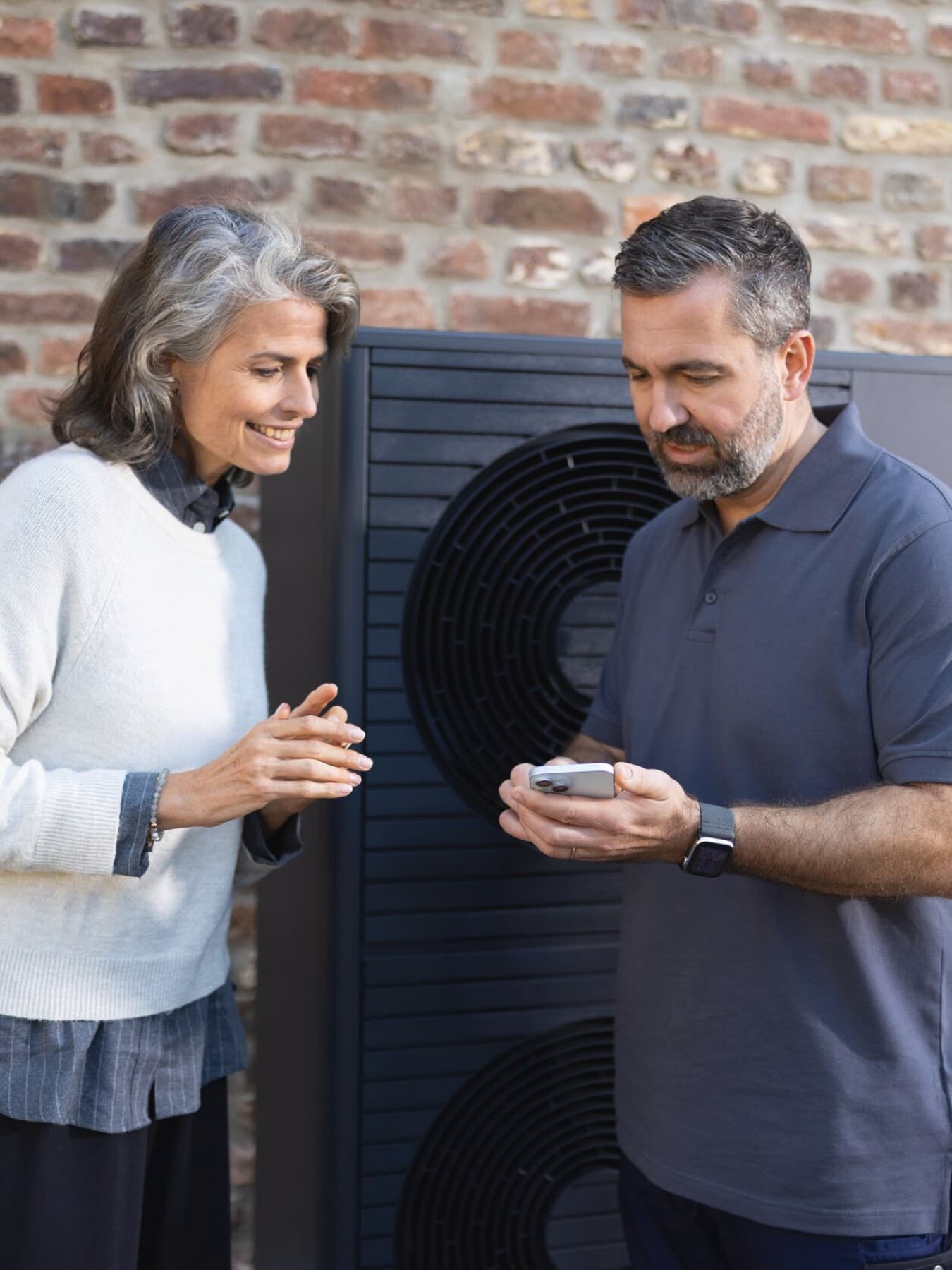 Isı pompasının önünde bir kadına myVAILLANT uygulamasını anlatan montajcı
